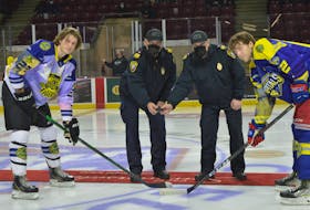 Summerside fire Chief Ron Enman, left, and deputy chief Kenny Blanchard drop the puck for the ceremonial faceoff between Summerside Western Capitals foward Colby MacArthur and Campbellton Tigers forward Jordan Briere on Saturday, March 5. The Capitals and Tigers honoured first responders in the region during a pre-game ceremony as part of a league-wide initiative.

