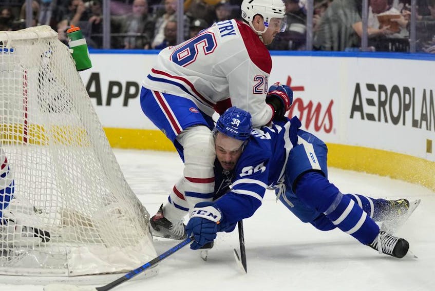 Maple Leafs' Auston Matthews (34) gets his stick on the puck as he battles Canadiens' Jeff Petry behind the net in Toronto on Saturday, April 9, 2022.