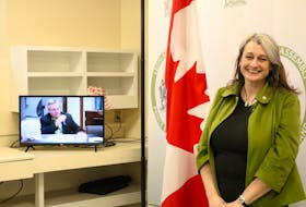 Green MLA Hannah Bell, seen here next to a live feed of the P.E.I. legislature, believes the P.E.I. government is one of the few jurisdictions in Canada that does not track purchases of real estate by investors. 