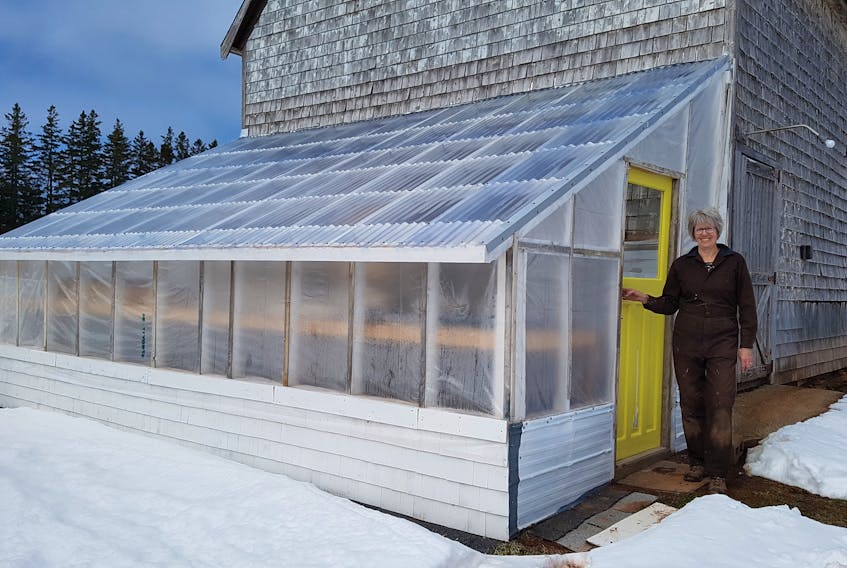 Heather MacLean of St. Peters Bay, P.E.I., stands in front of the greenhouse she built in late 2021.