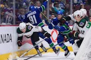  Arizona Coyotes’ Nathan Smith (13) and Vancouver Canucks’ Juho Lammikko (91), of Finland, collide during the first period of an NHL hockey game in Vancouver, on Thursday, April 14, 2022.