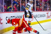  Vegas Golden Knights right wing Keegan Kolesar (55) checks into the boards Calgary Flames defenseman Christopher Tanev (8) during the first period at Scotiabank Saddledome.