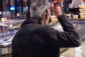 A man sips soup from a ladle at a supermarket buffet in this YouTube video. 