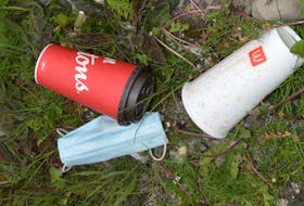 Two cups and a disposable mask are seen near a brook off Grand Lake Road in Sydney. Chris Connors/Cape Breton Post