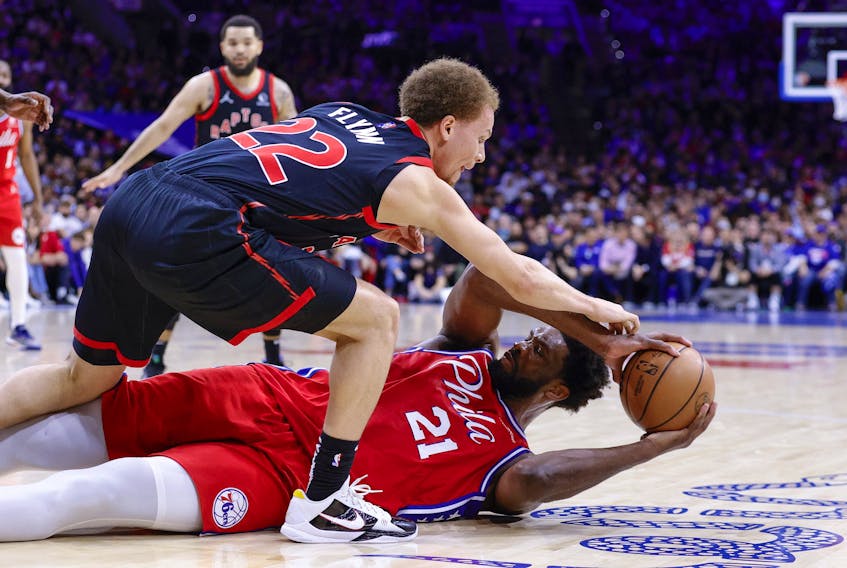 Philadelphia 76ers' Joel Embiid (right) battles from the floor for the ball with Raptors' Malachi Flynn during the first quarter of Game 2 of their Eastern Conference first-round series at Wells Fargo Center on Monday, April 18, 2022 in Philadelphia.