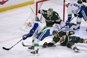  Vancouver Canucks right winger Alex Chiasson, left, tries to get the puck past Minnesota Wild right wing Ryan Hartman, right, and goalie Cam Talbot during the first period of an NHL hockey game Thursday, April 21, 2022, in St. Paul, Minn.