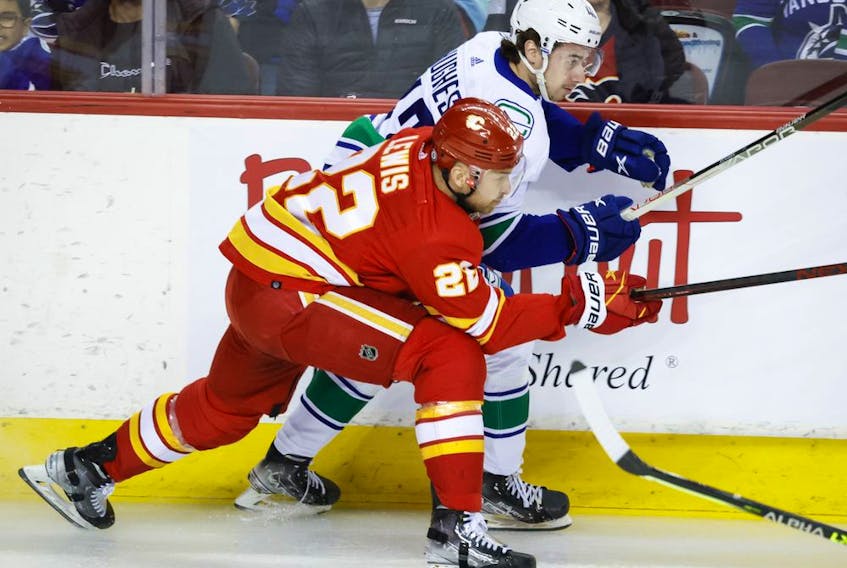  Vancouver Canucks defenceman Quinn Hughes, right, is checked by Calgary Flames centre Trevor Lewis during first period NHL hockey action in Calgary, Saturday, April 23, 2022.