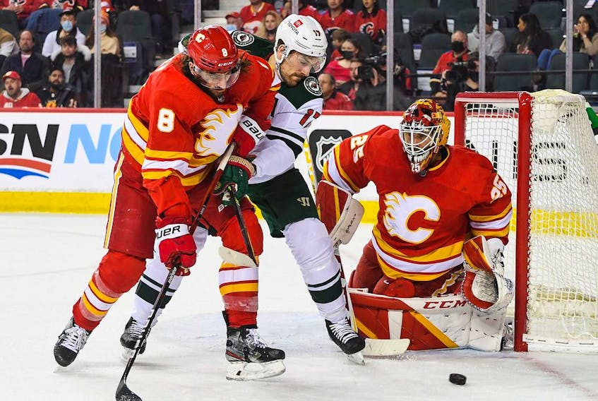 Calgary Flames defenceman Christopher Tanev and goaltender Jacob Markstrom defend the net against Minnesota Wild forward Marcus Foligno at Scotiabank Saddledome in Calgary on Saturday, Feb. 26, 2022.