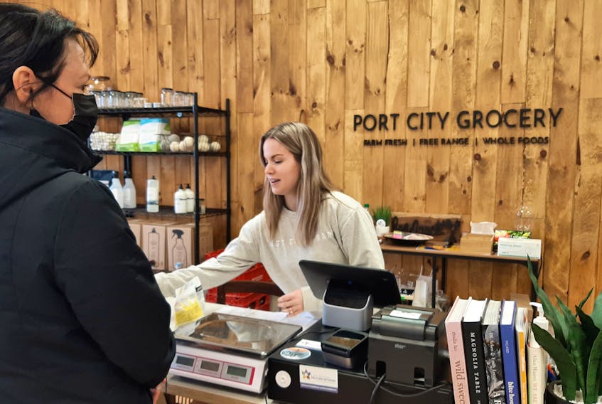 Kat Gouthro, co-owner of Port City Grocery on Charlotte Street in Sydney, chats with a customer as she bags up her purchases. Gouthro and her partner moved back to Cape Breton after seven years living in Edmonton, and opened their shop in 2021. "We feel grateful to be able to raise our family in Sydney." she said. ARDELLE REYNOLDS/CAPE BRETON POST