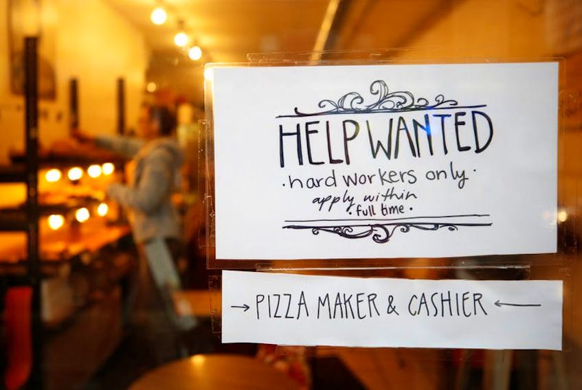 A "Help wanted" sign is seen in the window of a bakery. 