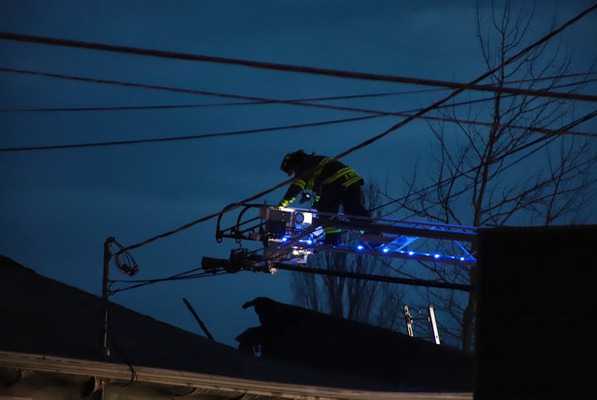 A member of the Charlottetown Fire Department assesses the damage from above the Brackley Point Road auto repair shop. Most of the roof of the shop was visibly destroyed.