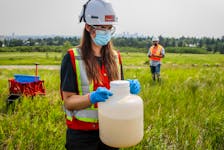  A City of Calgary industrial technician holds a jug of wastewater at a collection site as University of Calgary researchers check monitoring equipment for traces of COVID-19 in the wastewater system in Calgary, Alta. in July 2021.
