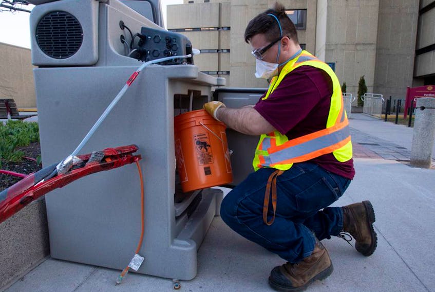  A student places a wastewater collection container inside a pump station on the University of Ottawa campus on April 8, 2021.