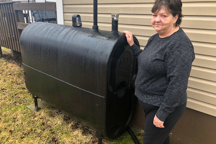 Eileen Oliver, 64, stands next to the oil tank on the side of her home on April 1. When thieves drained her tank of furnace oil Oliver was "devastated," unsure how she would get the month to re-fill it. NICOLE SULLIVAN/CAPE BRETON POST 
