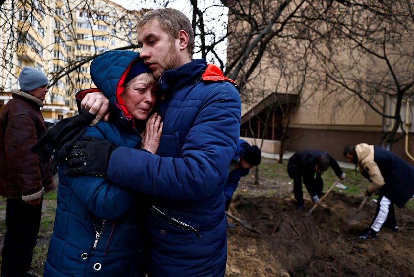 Serhii Lahovskyi, 26, hugs Ludmyla Verginska, 51, in Bucha, Ukraine on Tuesday as they mourn the burial of their common friend Ihor Lytvynenko, who, according to residents, was killed by Russian soldiers. His body was found beside a building's basement and he was buried at the garden of a residential building. REUTERS/Zohra Bensemra