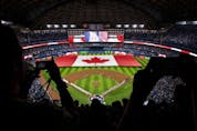 Fans cheer as a Canadian flag is unfurled on the field at the Rogers Centre during opening day for the Blue Jays on Friday. GETTY IMAGES