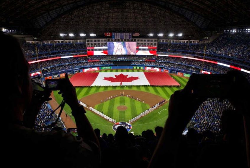 Fans cheer as a Canadian flag is unfurled on the field at the Rogers Centre during opening day for the Blue Jays on Friday. GETTY IMAGES