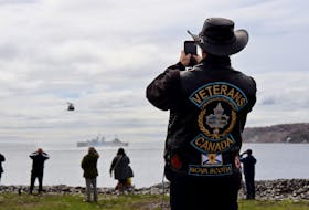 A man takes a photo of HMCS Sackville and a CH-148 Cyclone helicopter during a ceremony in Halifax on Sunday, May 1, 2022, to mark the anniversary of the Battle of the Atlantic.