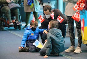 A father and his children wait at St. John’s International Airport Monday night for Ukrainian refugees to arrive in order to show their support.