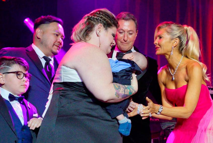  Guests of Honour Jonathon and Christine Fischer, right, meet the new baby carried by surrogate Samantha Audia for the Chen family, left, onstage at a fundraiser for the David Foster Foundation in Toronto, Ont., May 7, 2022.