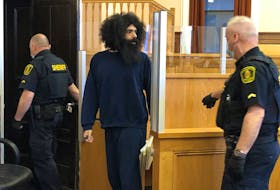Stephen Hopkins, who is representing himself at trial in Newfoundland and Labrador Supreme Court on charges related to an attack and sexual assault on a teenage girl in her St. John's home in 2020, speaks with amicus curiae John Brooks (not shown) before sheriffs escort him from the courtroom May 10. 