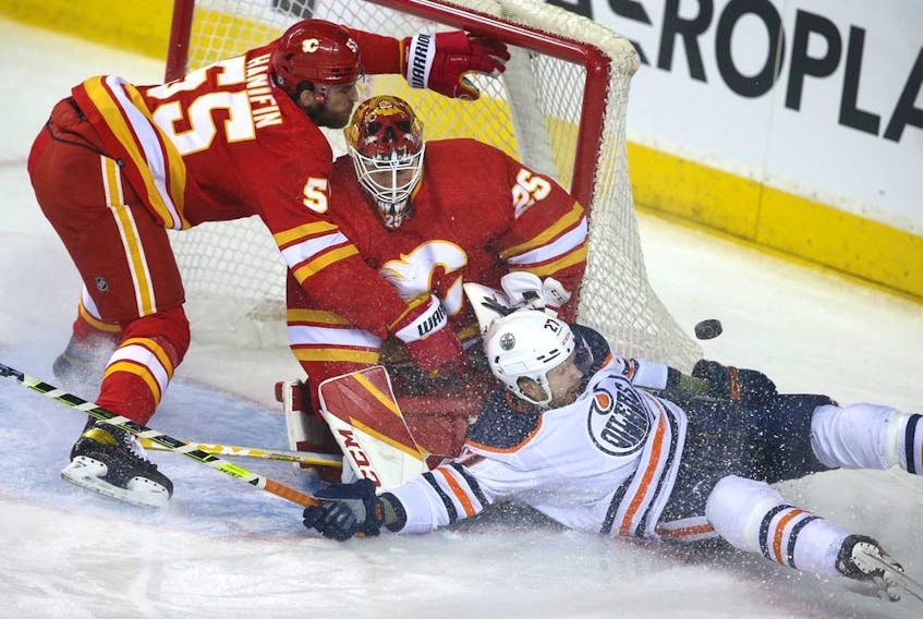 Edmonton Oilers defenceman Brett Kulak crashes into the net in front of Calgary Flames goaltender Jacob Markstrom and defenceman Noah Hanifin at Scotiabank Saddledome on March 26, 2022.