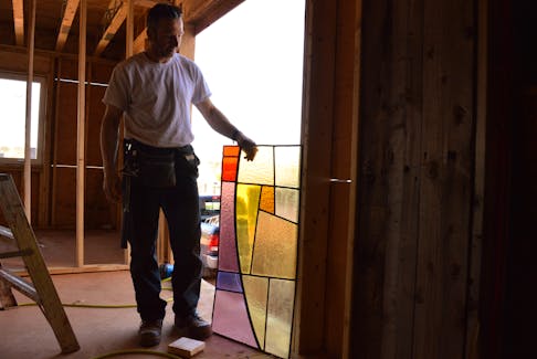 Kris Taylor holds a piece of the former St. Mary's Catholic Church's stained glass up to the light in Hunter River, May 12. Alison Jenkins • The Guardian