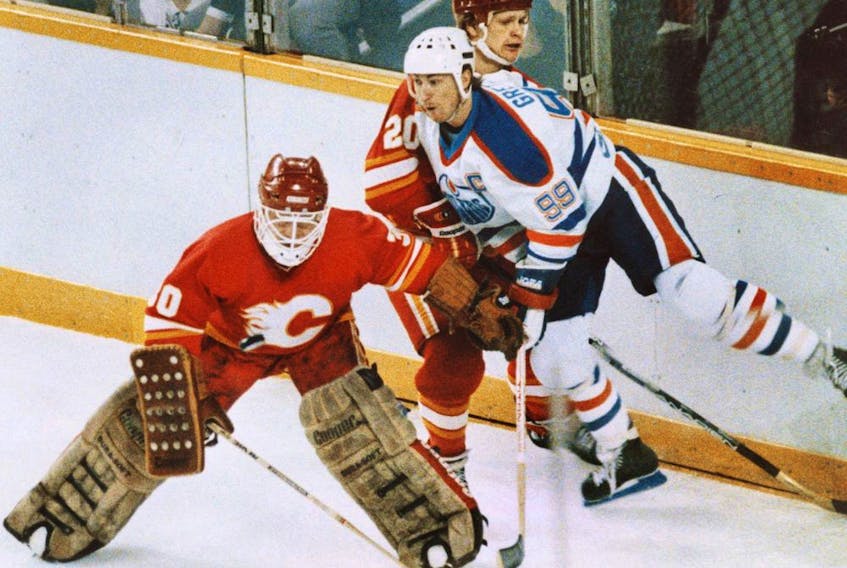 Edmonton Oilers forward Wayne Gretzky gets hit by Calgary Flames defenceman Gary Suter and goalie Mike Vernon during their 1986 playoff series.
