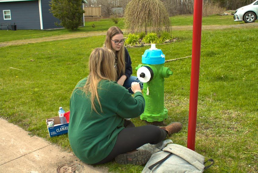Paige and Madison McLaughlin touch up a fire hydrant in Stellarton as part of NSCC's work in the community.