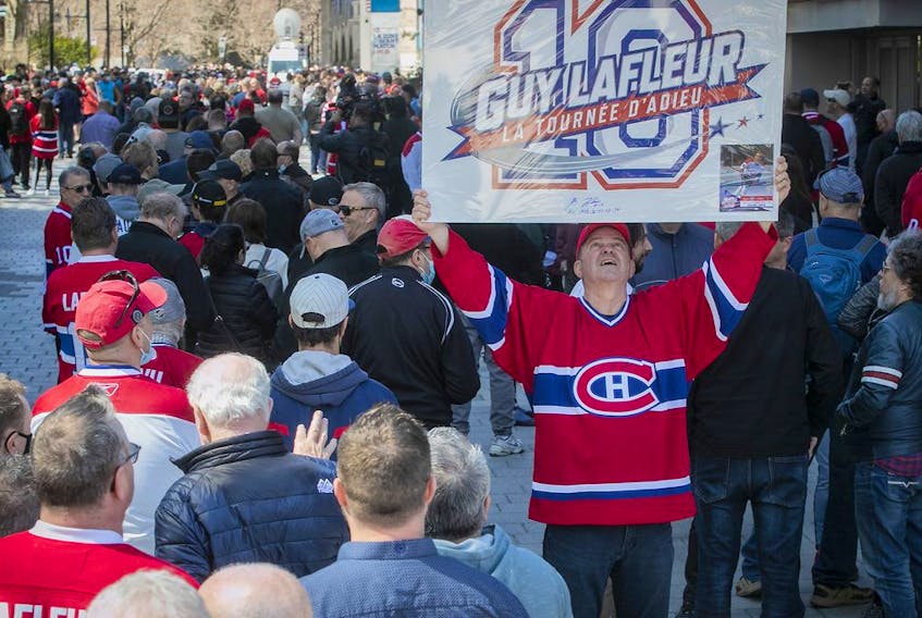Louis Theberge, a fan of Guy Lafleur, displays a sign as he waits along  Canadiens-de-Montréal Ave. on Sunday May 1, 2022, prior to the opening of the Bell Centre, where Lafleur's body was lying in state.