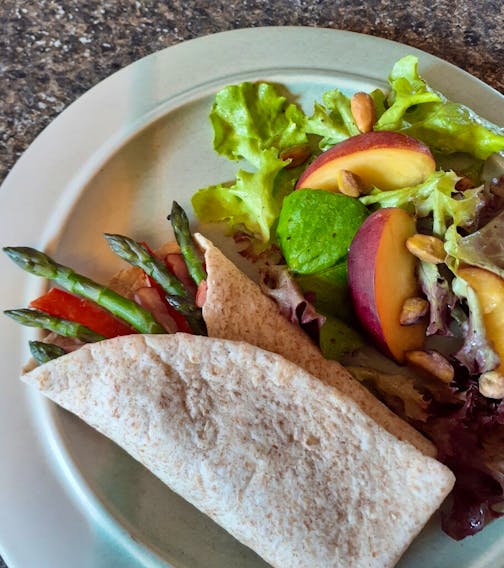 This whole wheat wrap with fresh asparagus, herbed Boursin cheese, red pepper strips and slivers of ham is served with salad of mixed greens, nectarine and pistachios.