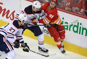 Dillon Dube of the Calgary Flames fights for a puck against centre Ryan McLeod of the Edmonton Oilers during the third period of action as the Calgary Flames lost to the visiting the Edmonton Oilers 5-3 in Game 2 of the second round of the Stanley Cup Playoffs at the Saddledome. Friday, May 20, 2022. Brendan Miller/Postmedia
