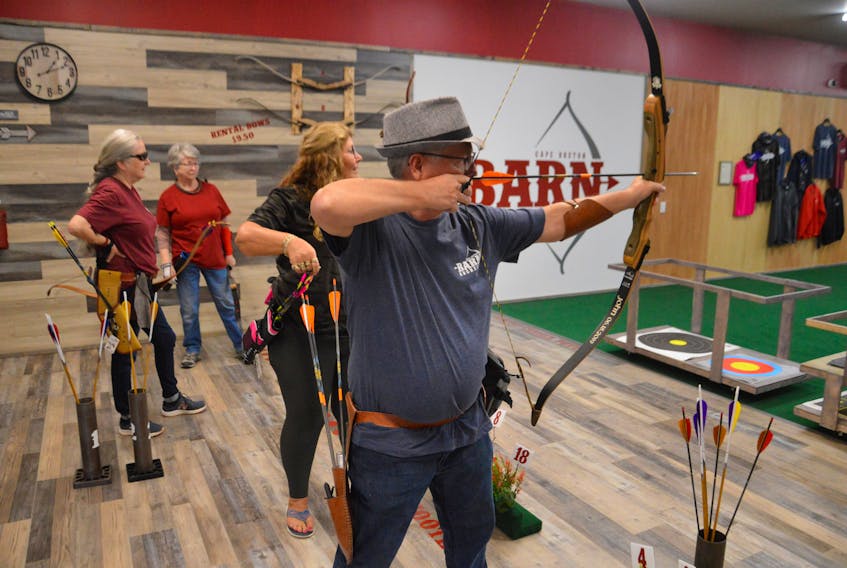 Cape Breton Barn Archers owner Bridget Benz and Elsie MacKinnon of Sydney watch Karen Cann and her husband, John Cann, prepare to shoot targets during the grand opening of the facility at French Road, near Gabarus. IAN NATHANSON/CAPE BRETON POST