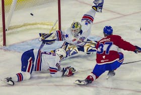 Brandon Gignac of the Laval Rocket scores on goalie Aaron Dell of the Rochester Americans at Place Bell in Laval on Monday, May 23, 2022. Defenceman Brandon Davidson also tries to stop the shot.