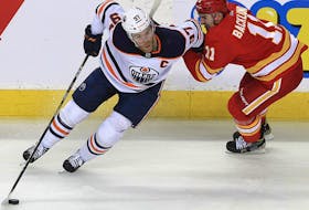 Connor McDavid of the Edmonton Oilers twists away from Flames forward Mikael Backlund in Game 2 on Friday, May 20.