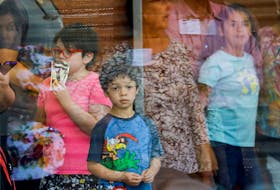 A child looks on through a glass window from inside the Ssgt. Willie de Leon Civic Center, where students had been transported from Robb Elementary School after a shooting, in Uvalde, Texas on Tuesday, May 24, 2022. - Marco Bello / Reuters
