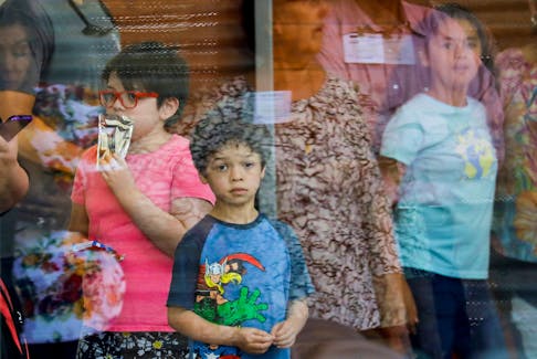 A child looks on through a glass window from inside the Ssgt. Willie de Leon Civic Center, where students had been transported from Robb Elementary School after a shooting, in Uvalde, Texas on Tuesday, May 24, 2022. - Marco Bello / Reuters