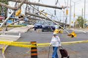 A woman walks around barricades on Merivale Road with downed power lines caused by last weekend's storm. Tuesday, May. 24, 2022.