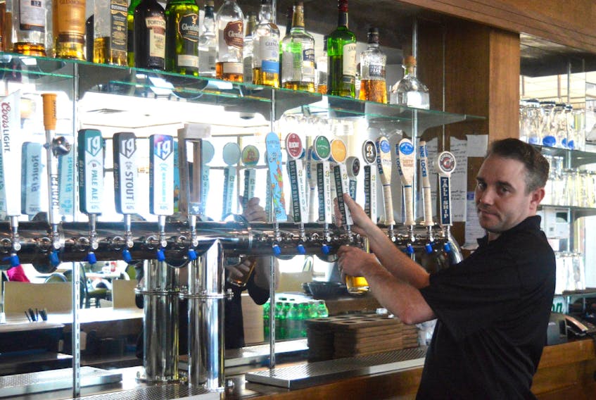 Jordan Hynes, bar manager for the Boardwalk Taproom and Eatery, serves up a beverage at the Sydney waterfront restaurant owned by Danny Ellis. Finding labour to work at food and beverage establishments ahead of the tourist season continues to be a struggle, Ellis says. IAN NATHANSON/CAPE BRETON POST