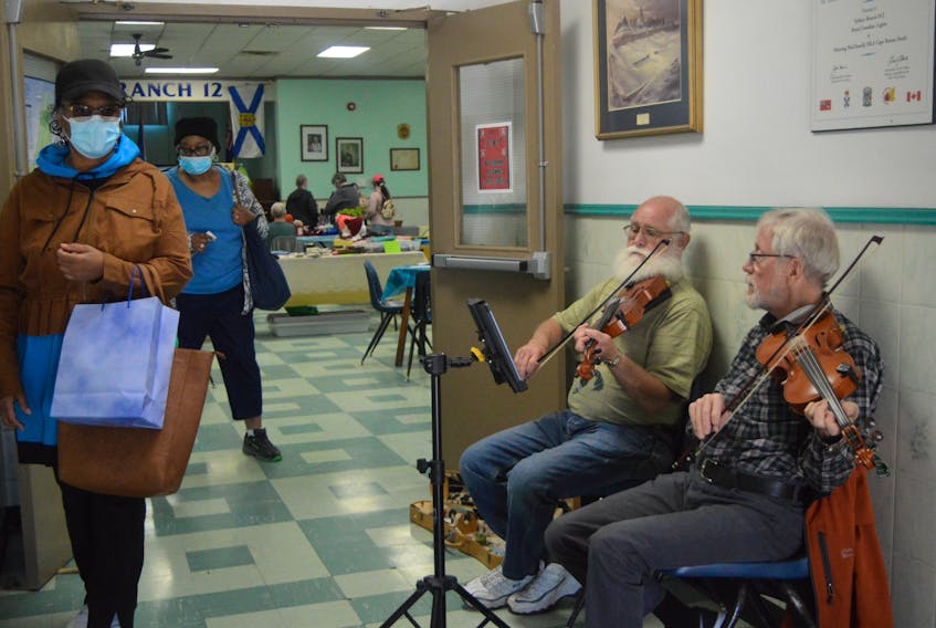 Royal Canadian Legion Branch 12 in Sydney was the scene for a craft fair opened for the benefit of visiting cruise ship passengers aboard the Zaandam on Wednesday. Greeting visitors at the door with some fiddle tunes were Carl Smith of Sydney, left, and Kevin McVarnish of South Bar. CAPE BRETON POST STAFF