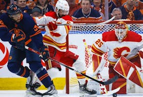 Calgary Flames defenceman Oliver Kylington, centre, checks Edmonton Oilers winger Evander Kane as goalie Jacob Markstrom follows the puck during Game 3 of their second-round playoff series at Rogers Place in Edmonton on Sunday, May 22, 2022.