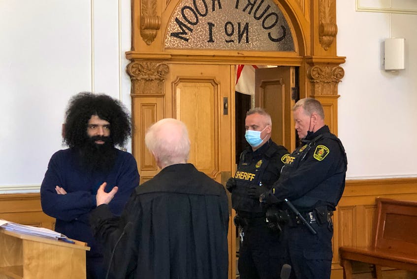 Stephen Hopkins (left), who is on trial for an attack and sexual assault of a St. John's teenager in her own home in September 2020, speaks with amicus curiae John Brooks as sheriffs wait to escort him back to the lockup during a break in proceedings Thursday, May 26.