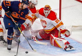 Edmonton Oilers Connor McDavid (97) battles with Calgary Flames Noah Hanifin (55) in front of goaltender Jacob Markstrom (25) during first period NHL second round playoff hockey action on Sunday, May 22, 2022 in Edmonton. 