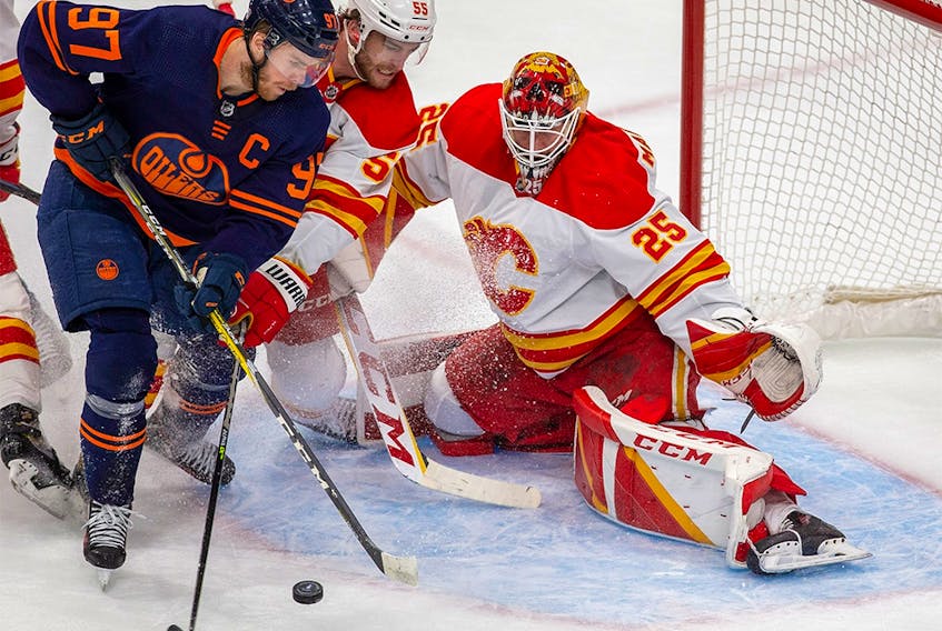 Edmonton Oilers Connor McDavid (97) battles with Calgary Flames Noah Hanifin (55) in front of goaltender Jacob Markstrom (25) during first period NHL second round playoff hockey action on Sunday, May 22, 2022 in Edmonton. 