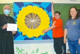 Father Roman Dusanowskyj, from left, accepts a painting of a sunflower on behalf of the Holy Ghost Ukrainian Catholic Church in Whitney Pier on Tuesday from Scar Doucette, 11, of Whitney Pier and Youth Peer Program art teacher Susanne Donovan. Doucette and other participants in the Youth Peer Program spent more than a month creating a 16-square-foot painting of the sunflower, the national flower of Ukraine. CHRIS CONNORS/CAPE BRETON POST