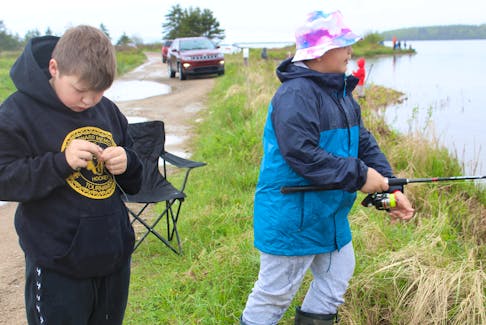 Spencer Paul, left, and Justin Paul, both 11 years old, focus on their tasks at the fishing derby in Eskasoni on Saturday afternoon. Both boys are experienced fishers and said they were hoping to win the grand prize of $5000. Ardelle Reynolds/Cape Breton Post