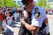 Edmonton police Chief Dale McFee hugs Dr. Holly Mah, Chair of Chinatown and Area Business Association, as they take part in a Chinatown safety rally outside City Hall, in Edmonton, Saturday, May 28, 2022. David Bloom-Postmedia