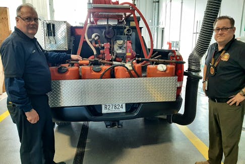 Firefighter Mark Bettens, left, and deputy fire chief Chris March, right, of the Sydney Fire Station on George St. check the water tanks on the back of the department's brush truck used to put out grass fires.