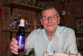 Donald Andrews holds up his unopened bottle of Silver Jubilee Ale from 1977. The bottle has never been opened, but sits on display in the basement of his Summerside house.