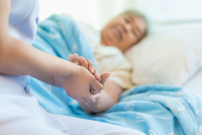 Nurse sitting on a hospital bed next to an older woman helping hands, care for the elderly concept  Nova Scotia announced it has hired 350 new nurses. Stock Photo.